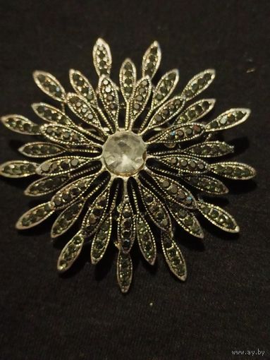 Винтажная брошь-цветок в форме ромашки или хризантемы с темными кристаллами имитирующими марказиты, и крупным светлым кристаллом в центре.