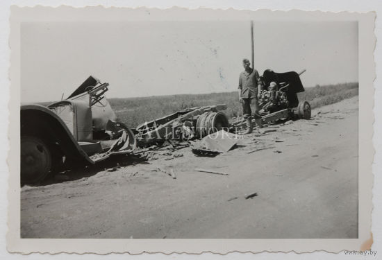 Немецкий солдат у сгоревших советских автомобиля и 76-мм дивизионной пушки образца 1939 года.